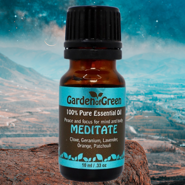 Meditate essential oil blend front view with the bottle sitting on a rock and the background is blue skies and mountains in the back ground with a city below
