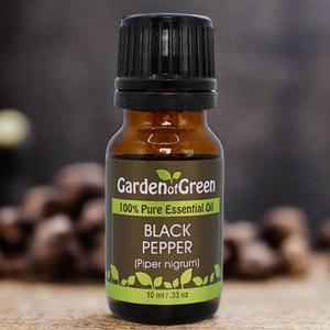 Black Pepper Garden of green essential oil front view sitting on a wood table with whole black pepper corn in the background