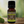 Clary Sage Garden of green essential oil front view sitting on a wood table with a leaf on the lower left hand side. kitchen in the background with a diffuser and a plant