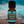 Meditate essential oil blend front view with the bottle sitting on a rock and the background is blue skies and mountains in the back ground with a city below