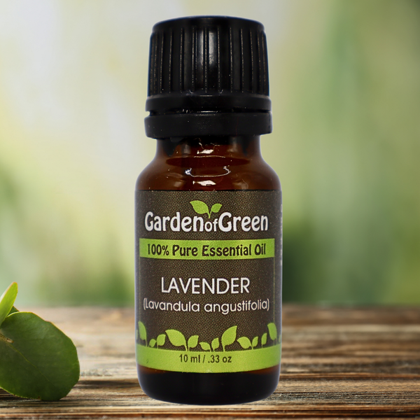 Lavender Garden of green essential oil front view sitting on a wood table with a leaf on the lower left hand side. green background with sun shining through the top left.