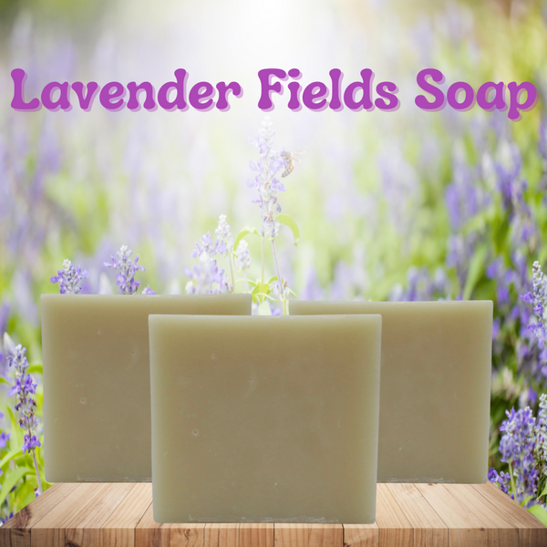 the title "lavender fields soap" is at the top of the page in a light purple/pink . 3 bars of soap are standing up right on a light wood table with a lavender field in the background with the sun shinning through the top