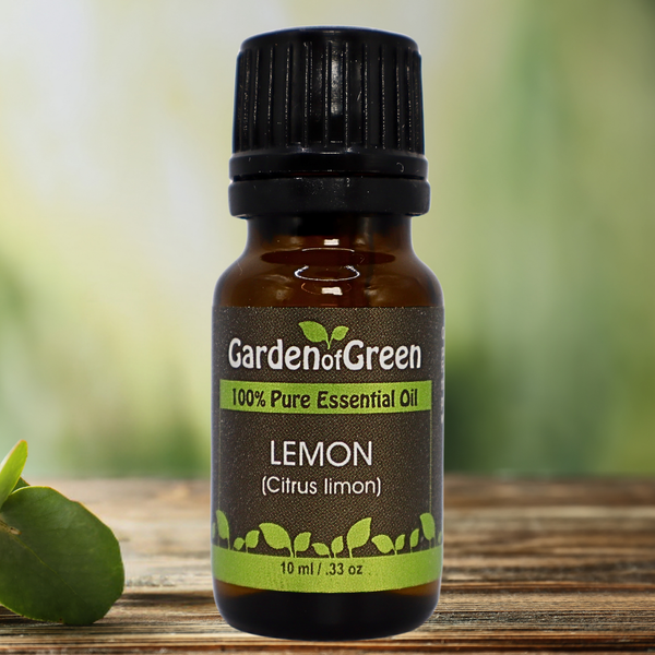 Lemon Garden of green essential oil front view sitting on a wood table with a leaf in the background  with a lemon on the right side