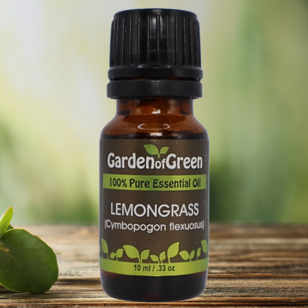 Lemongrass Garden of green essential oil front view sitting on a wood table with a leaf on the lower left hand side. green background with sun shining through the top left.