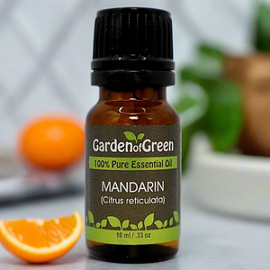 mandarin Garden of green essential oil front view sitting on a  counter with a mandarin slice next to it with greenery in the background