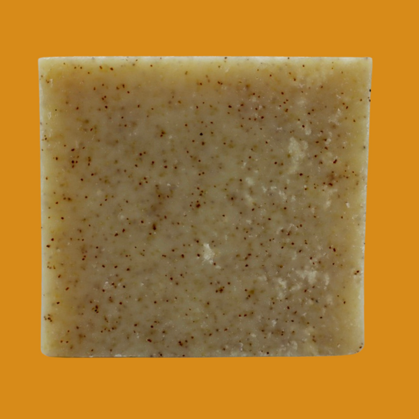 Garden of Green's oatmeal apricot bar soap plain view standing up like a square. the background is orange