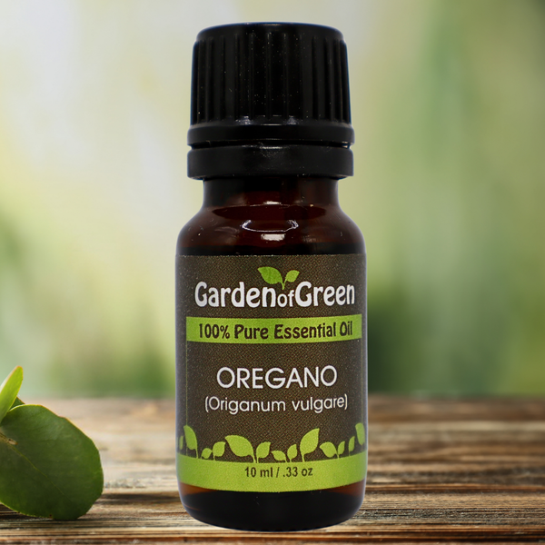 Oregano Garden of green essential oil front view sitting on a wood table with a leaf on the lower left hand side. green background with sun shining through the top left.