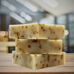 Three bars of handmade soap with a speckled pattern, stacked on top of each other on a wooden surface.