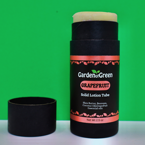 garden of green's grapefuit solid lotion tube front view sitting on a white table with a green background