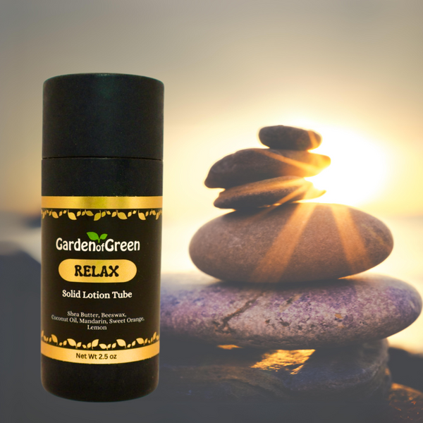 Garden of Green's Relax solid lotion tube front view sitting on a big rock with a stack of rocks on the righthand side with the sun shinning through the rocks all with a yellow sky background