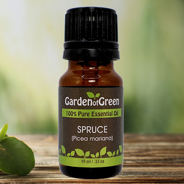 Spruce Garden of green essential oil front view sitting on a wood table with a leaf on the lower left hand side. green background with sun shining through the top left.