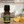 Sweet Orange essential oil front view sitting on a wood table in the kitchen sliced oranges on the right side of it.
