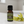 Ylang Ylang essential oil essential oil in amber glass bottle, family-crafted aromatherapy oil, front view on a white surface with yellow flowers.
